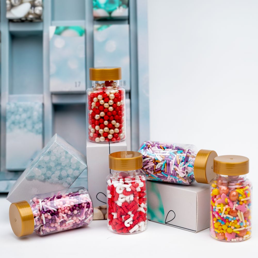 Sallys Adventskalender – verschiedene bunte Streuselmischungen in kleinen Dosen vor geöffneten Türchen