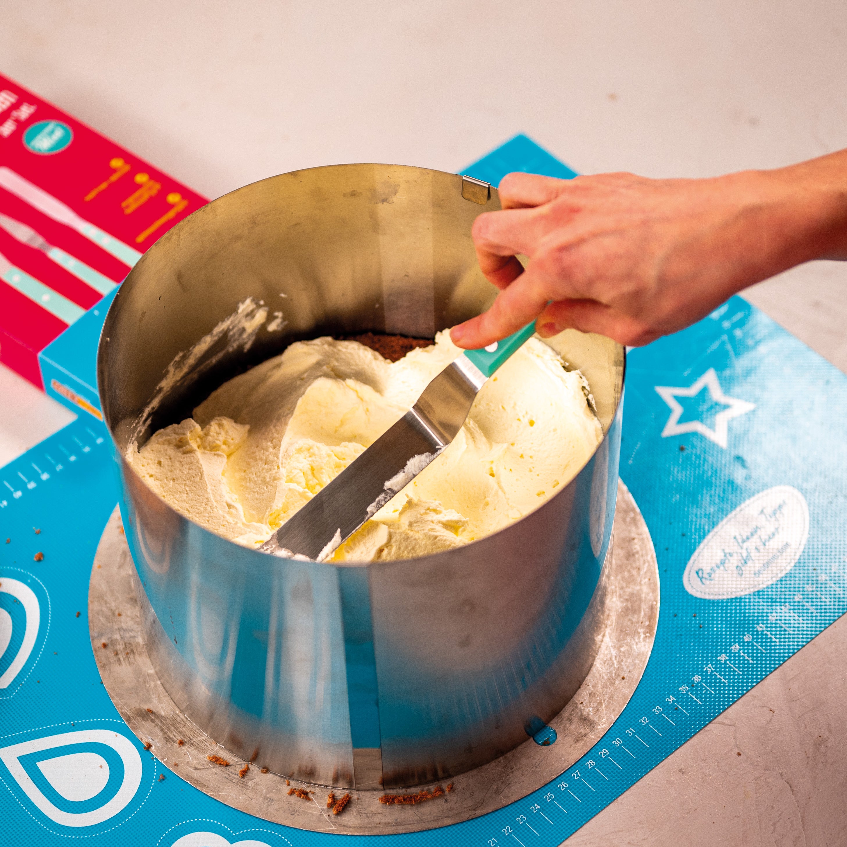 Torte wird mit der langen Decocino Winkelpalette im Tortenring mit Creme gefüllt.