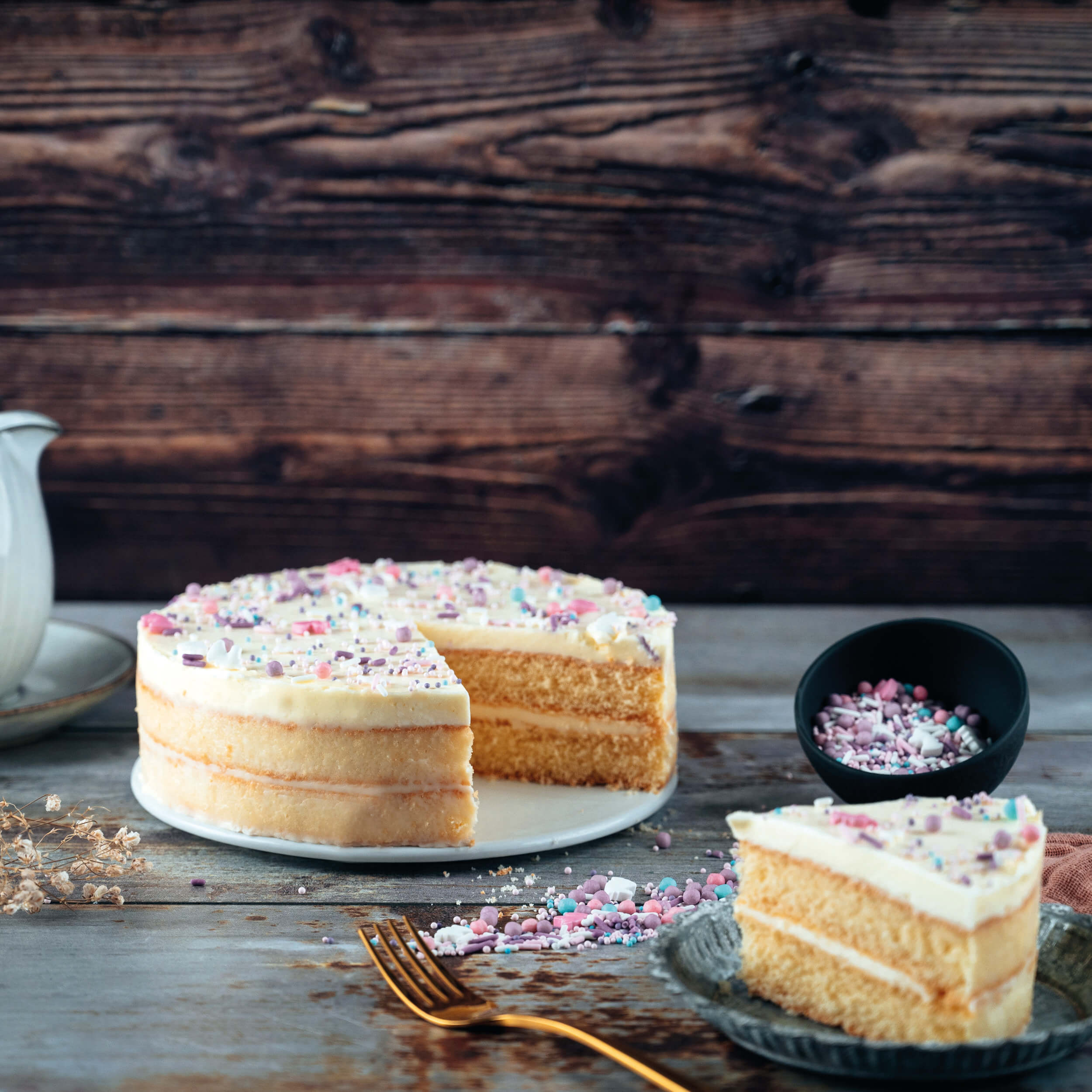 Anschnitt einer hellen Vanilletorte mit Cremefüllung und bunten Streuseln