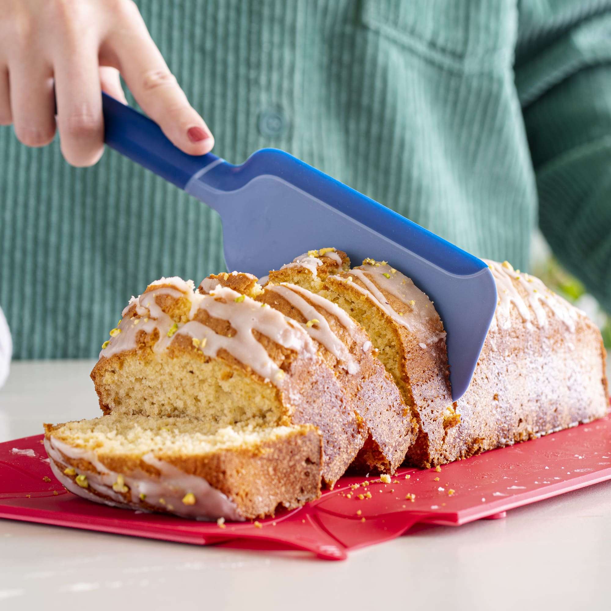 Blauer Schneidheber schneidet einen saftigen Rührkuchen in Scheiben.
