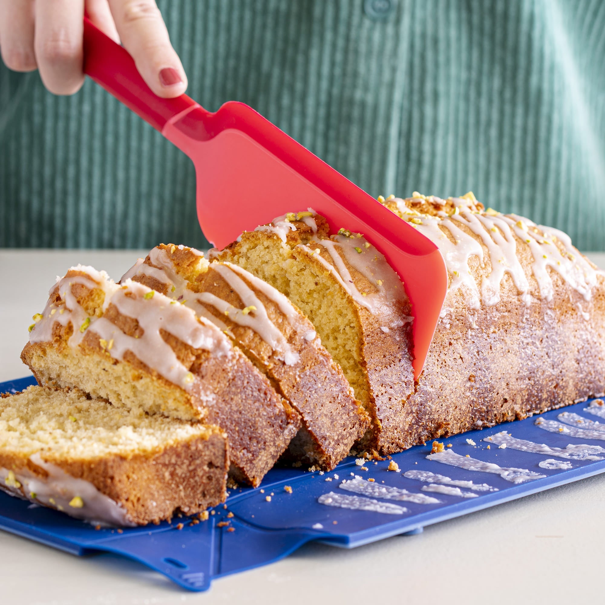Roter Schneidheber schneidet einen saftigen Rührkuchen in Scheiben.
