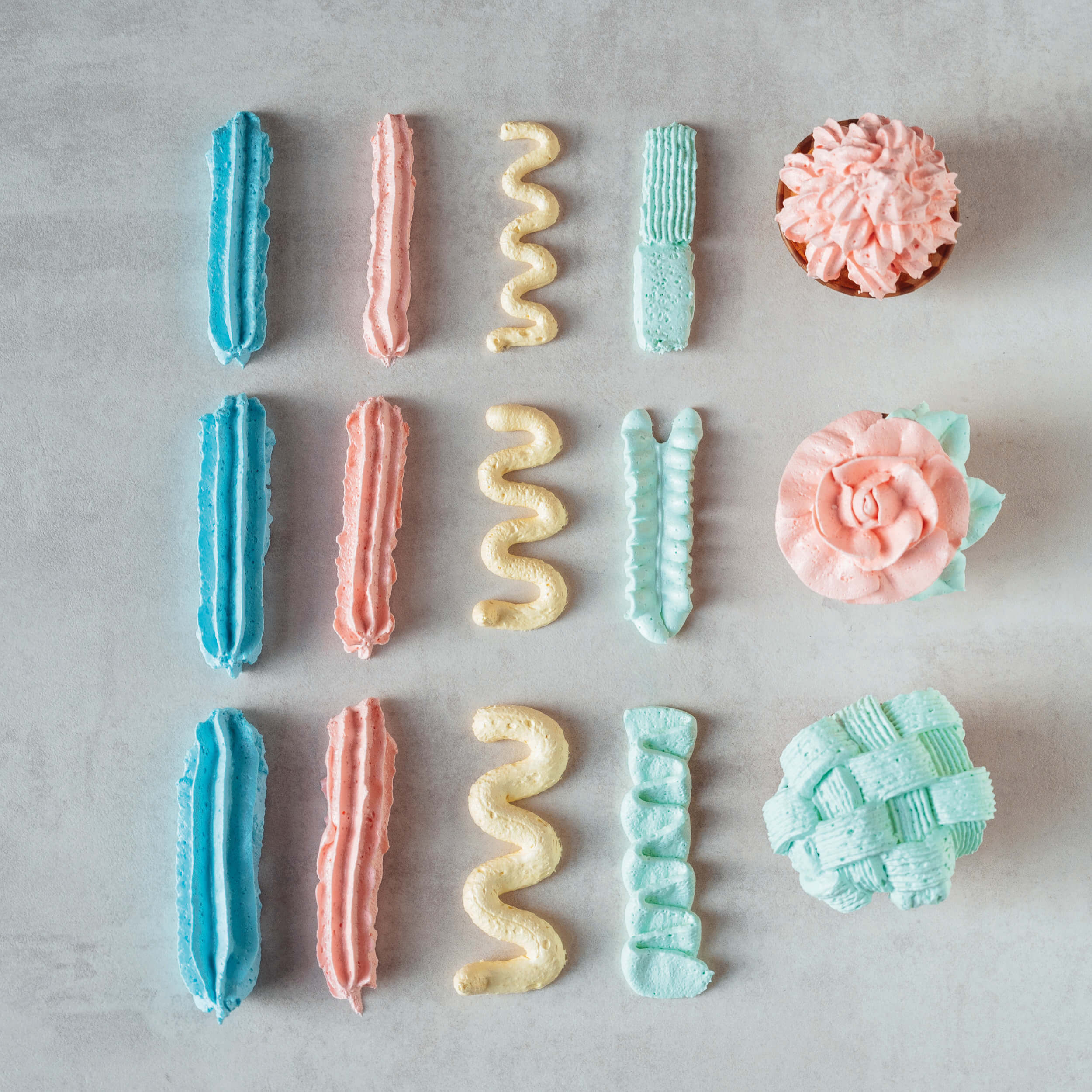 Buttercreme-Dekorationen in verschiedenen Farben und Formen, gespritzt mit einer Spritztülle von Decocino