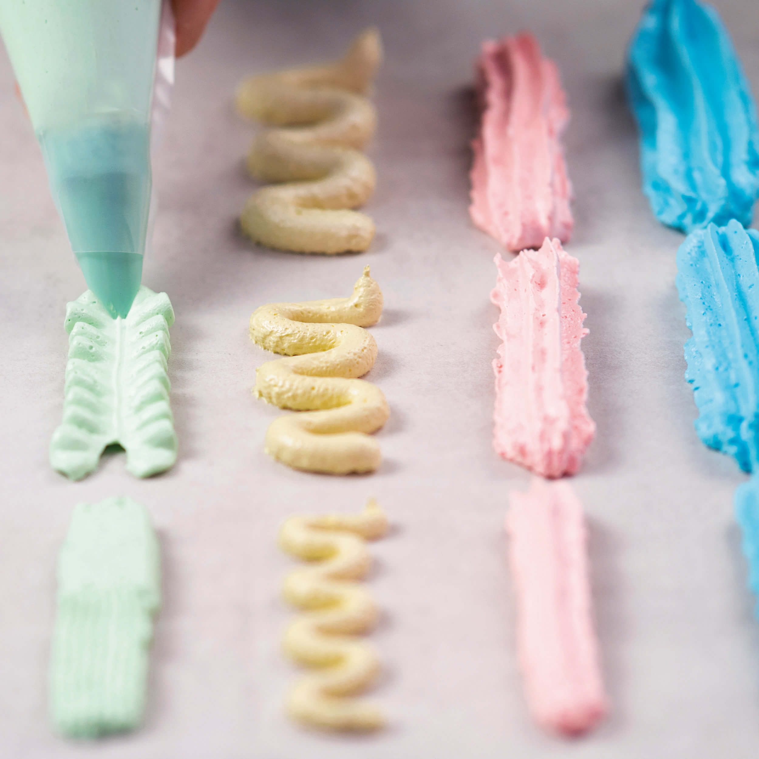 Buttercreme-Dekorationen in verschiedenen Farben und Formen, gespritzt mit einer Spritztülle von Decocino